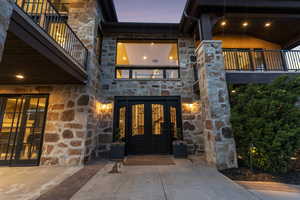 Entrance to property with stone siding, french doors, and a balcony