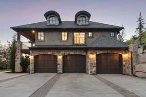 French provincial home featuring stone siding, concrete driveway, stucco siding, and a shingled roof