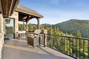 Balcony with an outdoor kitchen, a mountain view, and a wooded view
