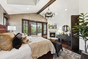 Bedroom with dark wood-style floors, a warm lit fireplace, a chandelier, and recessed lighting