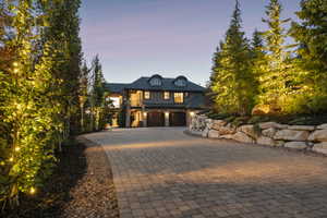 French country style house featuring decorative driveway, stone siding, and an attached garage