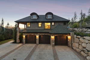 French country home with concrete driveway, stucco siding, stone siding, and roof with shingles