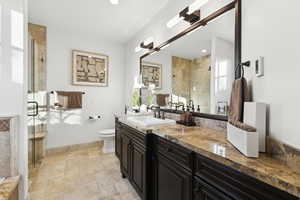 Bathroom featuring vanity, a shower stall, stone tile floors, and recessed lighting