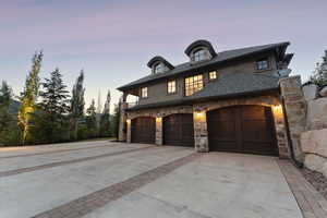 View of front of property featuring concrete driveway, stone siding, and stucco siding