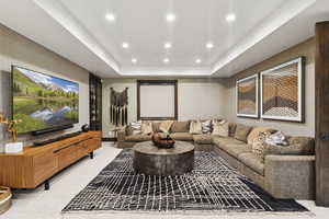 Home theater with a raised ceiling, recessed lighting, and light carpet