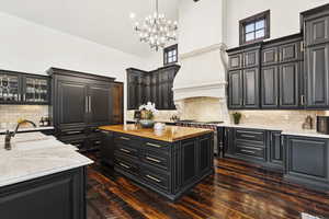 Kitchen with dark cabinetry, backsplash, a center island, wooden counters, and dark wood finished floors