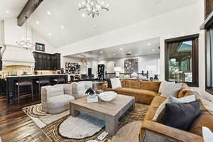 Living room featuring a chandelier, high vaulted ceiling, dark wood-style flooring, beamed ceiling, and recessed lighting