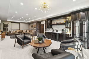 Living room featuring recessed lighting, wet bar, light carpet, a chandelier, and a raised ceiling