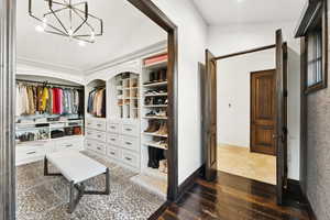Spacious closet featuring dark wood-type flooring, vaulted ceiling, and a chandelier