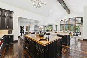 Kitchen with a chandelier, a large island with sink, open floor plan, dark cabinets, and butcher block countertops