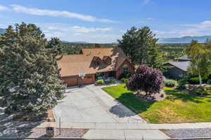 View of front of property featuring a mountain view, an attached garage, concrete driveway, and a chimney