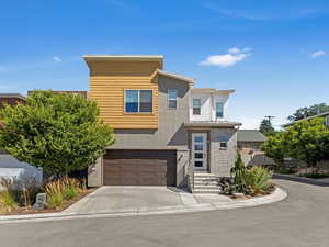 Modern home featuring concrete driveway, an attached garage, brick siding, and stucco siding
