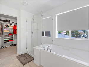 Bathroom featuring a shower stall, a walk in closet, and a bath