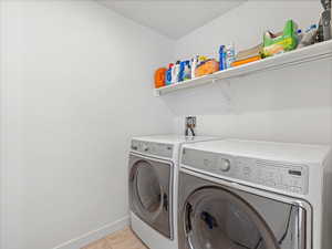 Laundry room featuring washing machine and clothes dryer and light tile patterned flooring