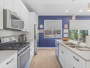 Kitchen featuring plenty of natural light, appliances with stainless steel finishes, light wood-style flooring, light countertops, and recessed lighting