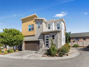 Contemporary house featuring an attached garage, stucco siding, stone siding, and concrete driveway