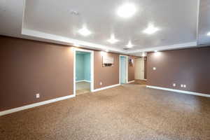 Unfurnished room featuring a raised ceiling, a textured ceiling, and light carpet