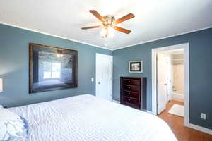 Bedroom featuring wood finished floors, ornamental molding, ceiling fan, and ensuite bath