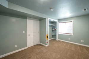 Unfurnished bedroom featuring carpet floors, a textured ceiling, and a closet