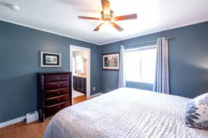 Bedroom featuring wood finished floors, a ceiling fan, and connected bathroom