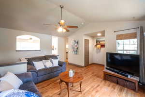 Living area featuring lofted ceiling, light wood-style floors, and a ceiling fan