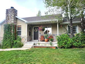 View of front of house with stone siding, roof with shingles, and a porch