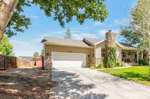 Ranch-style house featuring a garage, stone siding, driveway, and a chimney