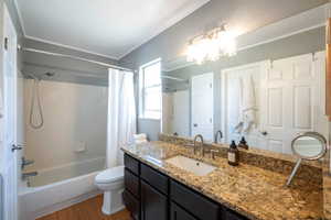 Full bathroom featuring shower / bathtub combination with curtain, vanity, wood finished floors, crown molding, and a chandelier