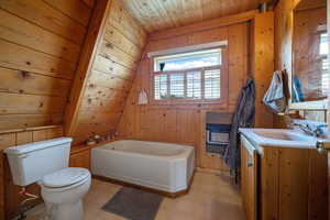 Bathroom featuring tile patterned floors, a bath, vanity, wood walls, and heating unit
