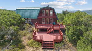 Rear view of property with a gambrel roof, a wooden deck, a metal roof, and stairway