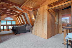 Carpeted bedroom featuring wooden walls and wood ceiling