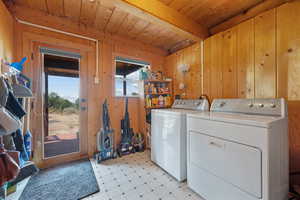 Laundry area featuring washer and dryer, wooden walls, light floors, and wooden ceiling