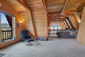 Carpeted bedroom with wooden walls and wooden ceiling