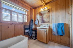 Full bathroom with tile patterned floors, wooden walls, a bath, vanity, and wooden ceiling