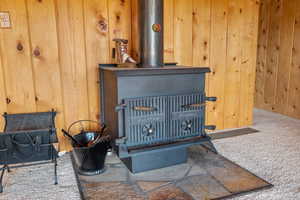 Detailed view of a wood stove, wood walls, and carpet floors