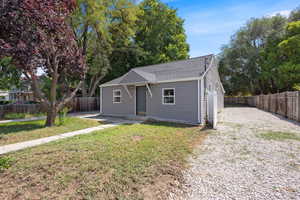 Bungalow featuring a shingled roof and a fenced backyard