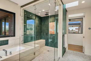 Bathroom featuring a bath, a shower stall, a skylight, and recessed lighting