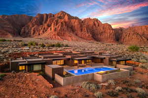 Pool at dusk with an outdoor fire pit, a mountain view, a patio area, and view of desert landscape