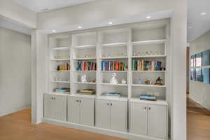 Detailed view of wood finished floors, recessed lighting, and built in shelves
