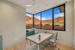 Home office featuring a mountain view, ceiling fan, and light wood-style floors