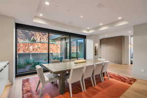 Dining space with a raised ceiling, light wood-style flooring, recessed lighting, and floor to ceiling windows