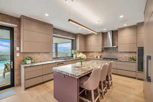 Kitchen featuring modern cabinets, gray cabinetry, a breakfast bar area, backsplash, and recessed lighting