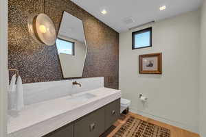 Bathroom featuring healthy amount of natural light, vanity, and wood finished floors