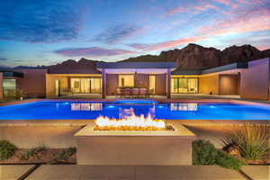 Pool at dusk with an outdoor fire pit, a patio, and a pool with connected hot tub