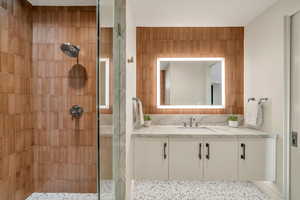 Full bath featuring tiled shower and vanity