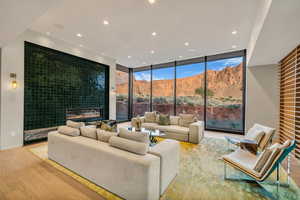 Living area featuring wood finished floors, expansive windows, a mountain view, recessed lighting, and a fireplace
