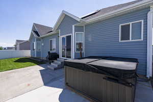 Rear view of property with a hot tub, a patio, and a shingled roof
