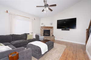 Living area featuring ceiling fan, wood finished floors, lofted ceiling, and a fireplace
