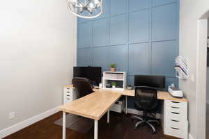 Living room used as office space with a decorative wall and a chandelier