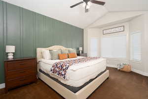 Bedroom with vaulted ceiling, dark colored carpet, and a ceiling fan